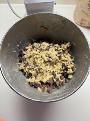 A mixing bowl with finished cookie batter and chocolate chips.