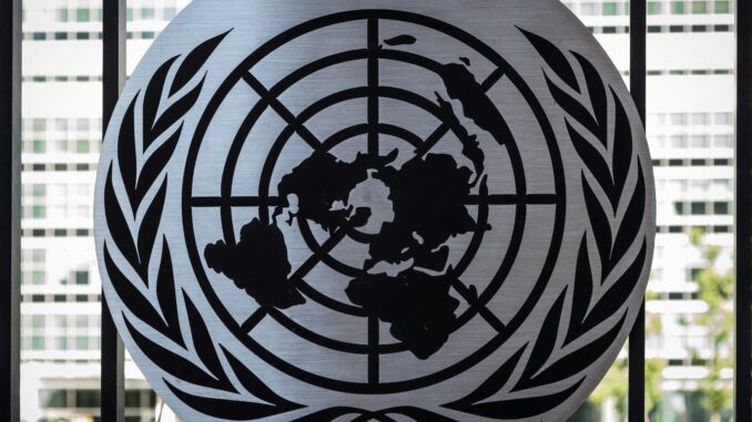 Model UN Unsplash photo The Model United Nations logo is on a silver circle with a city in the background. The logo itself has a map of the world with olive branches surrounding it.
