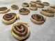 15 golden brown pie crust cinnamon rolls with melted sugar and cinnamon inside them sit evenly spaced on a sheet of parchment paper.