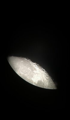 An up close view of the Earth’s moon. The moon is shown from its side, and craters are visible on the surface.