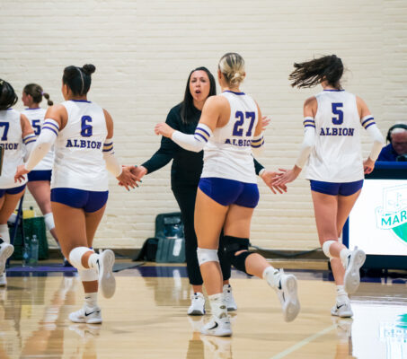 A coach high-fives players walking off a court.