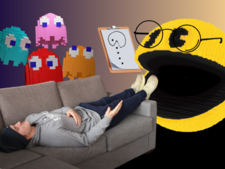 A young man lies on a gray couch, feet up on the arm and gesturing as he speaks. Behind him are four pixelated multicolored ghosts, who look over him. At his feet is a 3D pixelated Pac-Man wearing glasses and a clipboard with a picture of Pac-Man drawn on it.