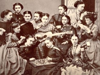 In the foreground of a black and white photo sit four women. The two in the center are playing chess, the one to the right of them is holding binoculars and the one to their left is sitting with a piece of paper in her hands. Behind them are nine other women; the ones in the center are sitting in a row, with the woman in the center playing guitar. The woman to the far left of her is holding some paper, and to the far right, a woman is getting her hair done up with a flower crown whilst reading a piece of paper. All the women are wearing Victorian-era hairstyles and clothing.
